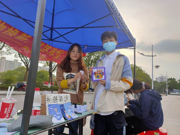 男孩交换亲手制作的编织品后与志愿者的合影留念